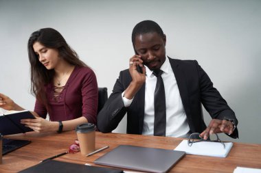 Modern ofiste birlikte çalışan genç ve mutlu iş adamları, çok ırklı takım çalışması. Akıllı telefondan arayan adam.