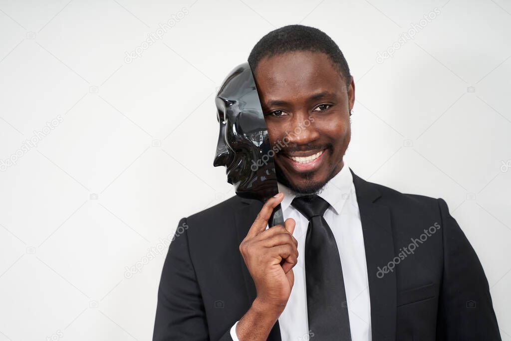 African young man wearing black suit taking off plastic mask revealing face and smiling