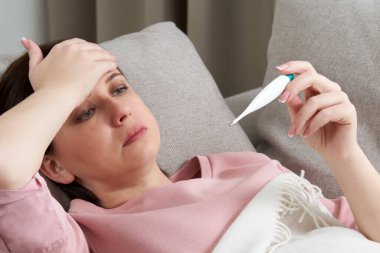 Elinde dijital termometre tutan bir kadın. Ateş, baca, virüs ve karantina kavramı 