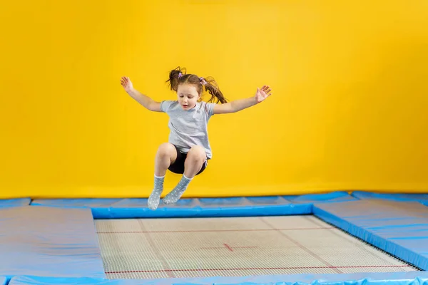 Feliz niña saltando en el trampolín en el gimnasio — Foto de Stock