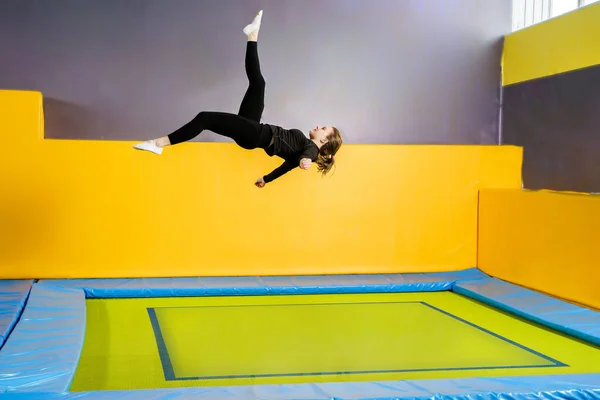 Jovencita aficionada atleta acrobática saltando y ejercitándose en un trampolín interior, hobby moderno y concepto de fitness —  Fotos de Stock