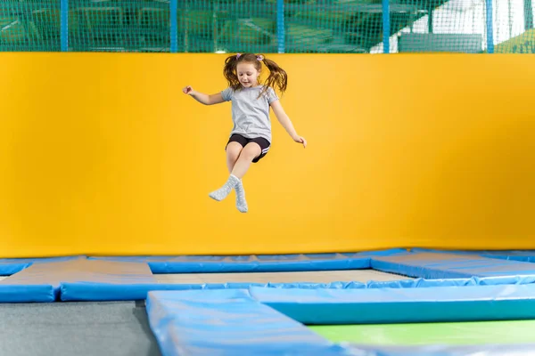 Happy little girl jumping on trampoline in fitness center — Stock Photo, Image