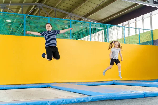 Glücklich lächelnde kleine Kinder springen auf Indoor-Trampolin im Vergnügungszentrum — Stockfoto
