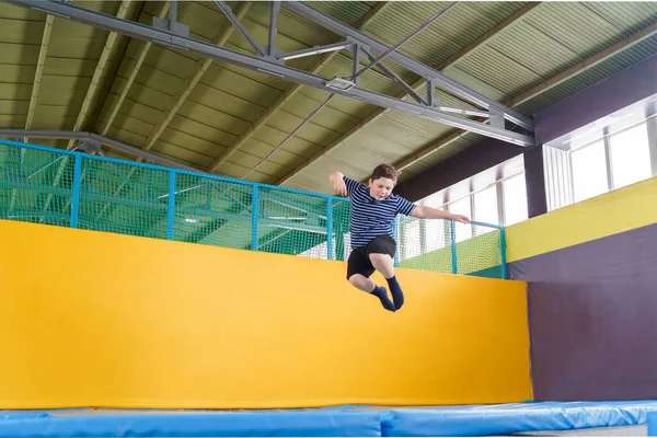 Sobrepeso bonito menino pulando no trampolim dentro de casa em um centro esportivo para crianças — Fotografia de Stock