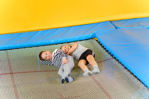 Feliz sonriente niños pequeños que ponen en el trampolín interior en el centro de entretenimiento —  Fotos de Stock