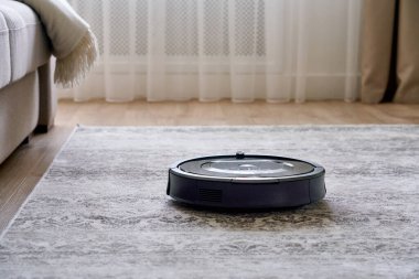Konforlu modern oturma odasının zemininde robot süpürge var.