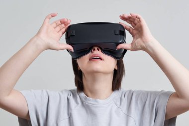 VR gözlükleriyle oynayan mutlu genç bir kadın, genç bir kızın kulaklıkla eğlendiği sanal gerçeklik konsepti, fotokopi alanı.