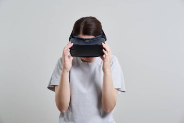 VR gözlükleriyle oynayan mutlu genç bir kadın, genç bir kızın kulaklıkla eğlendiği sanal gerçeklik konsepti, fotokopi alanı.