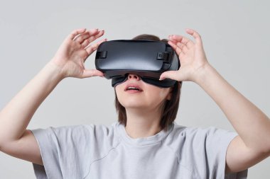 VR gözlükleriyle oynayan mutlu genç bir kadın, genç bir kızın kulaklıkla eğlendiği sanal gerçeklik konsepti, fotokopi alanı.