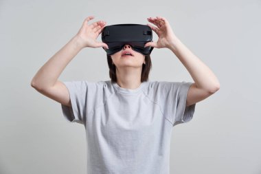 VR gözlükleriyle oynayan mutlu genç bir kadın, genç bir kızın kulaklıkla eğlendiği sanal gerçeklik konsepti, fotokopi alanı.