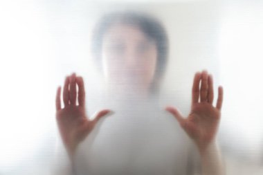 Kadın ellerinin dağınık silueti, plastiğin içinden gölgeli bir görüntü.
