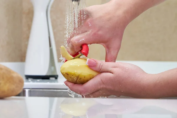 Mujer pelando patatas sobre un fregadero, vista de cerca — Foto de Stock