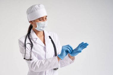Genç doktor beyaz arka planda cerrahi eldiven takıyor.