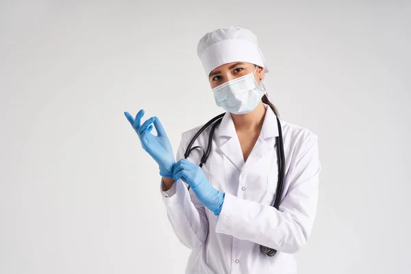 Молодой доктор надевает хирургические перчатки на белом фоне — стоковое фото