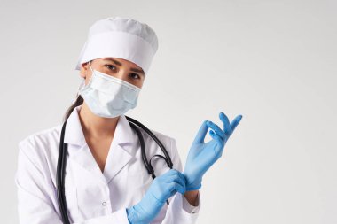 Genç doktor beyaz arka planda cerrahi eldiven takıyor.