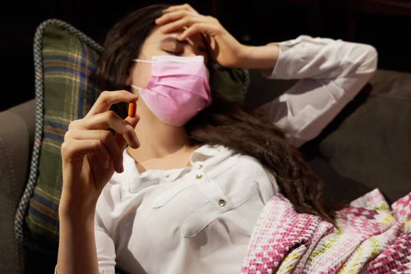 Kanepedeki genç kadın battaniyeyle örtülmüş, donarak burnu donuyor, ateşi var, hasta kız grip, grip ya da virüs belirtileri gösteriyor.