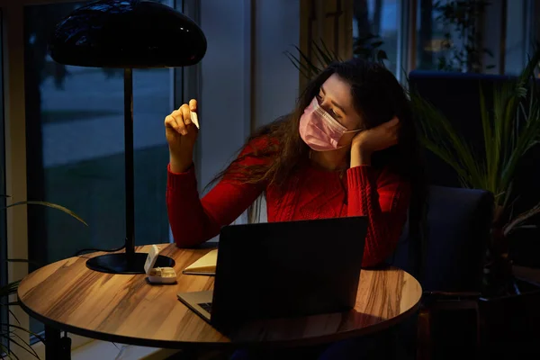 Chora kobieta z pigułkami i termometrem na stole pracująca na laptopie z domu na izolacji kwarantanny. — Zdjęcie stockowe