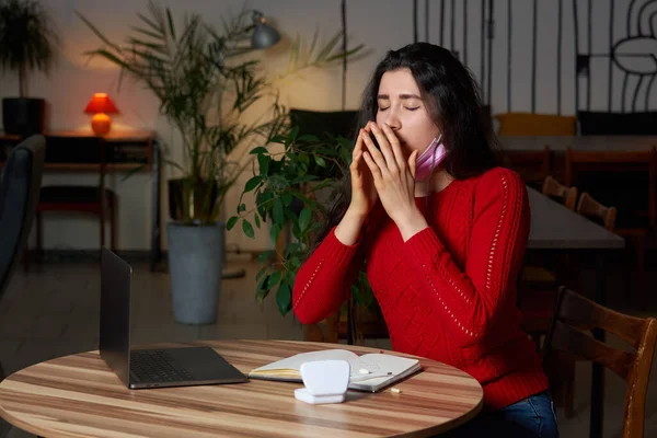 Chora kobieta kichająca pigułkami i termometrem na stole pracująca na laptopie z domu podczas kwarantanny. — Zdjęcie stockowe