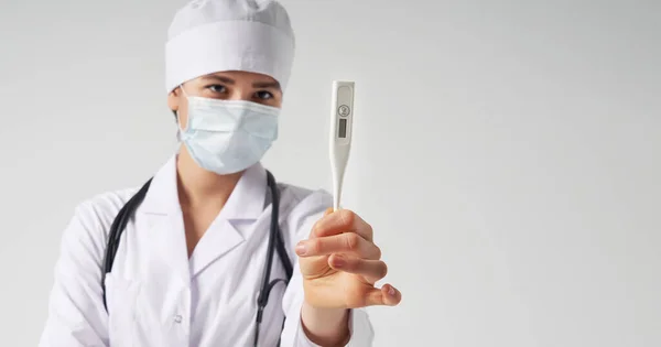 Junge Ärztin zeigt Thermometer vor weißem Hintergrund, Studioaufnahme — Stockfoto