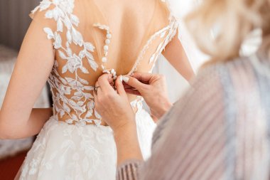 Anne geline gelinlik için yardım ediyor, törenden önceki gün için hazırlık yapıyor.