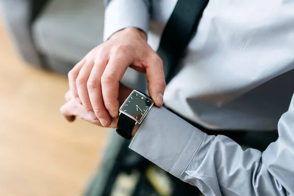 Un hombre con un traje de negocios revisando un reloj de pulsera en su mano — Foto de Stock