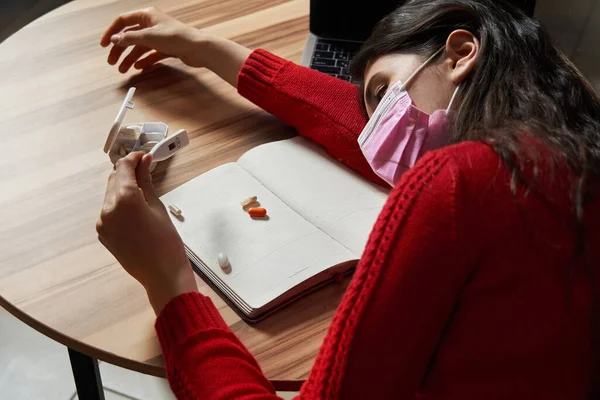 Evdeki karantina izolasyonunda dizüstü bilgisayarda çalışan ilaç ve termometresi olan hasta bir kadın.. — Stok fotoğraf