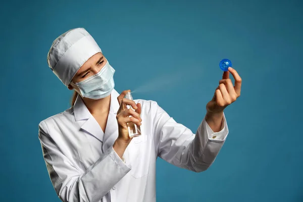 Doktorn håller Coronavirus blå modell och använda desinfektionsmedel spray för att döda den, studio skott med kopieringsutrymme — Stockfoto