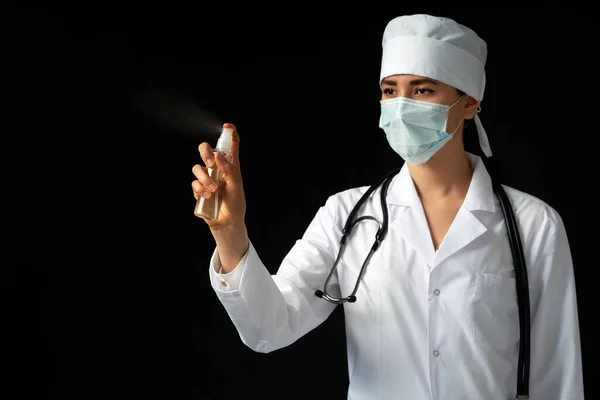 Ung kvinnlig läkare med spray antiseptisk spray över svart bakgrund med kopia utrymme — Stockfoto