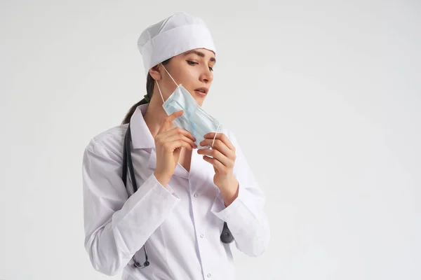 stock image Portrait of young female doctor putting on protective medical face mask on white background, copy space