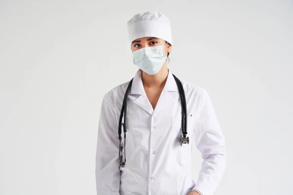 Портрет молодой женщины-врача в защитной маске на белом фоне, пространство для копирования — стоковое фото