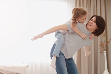 Mutlu anne kızını sırtında taşıyor. Genç kız evde iyi eğlenceler.