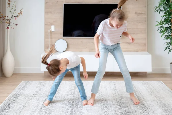 2人の姉妹がリビングルームで楽しいダンスをし、幸せな家族のコンセプト — ストック写真