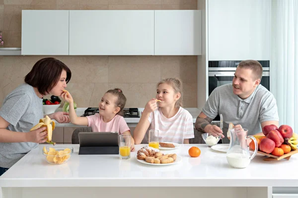 Smiling Family Dining Together at kitchen table and having fun, parents with two daughters