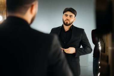 ciddi stil çekici sakallı genç adam dışarı çıkmadan önce resmi kıyafetler giyiyor.