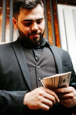 Sakallı genç adam cebine dolar koyuyor.