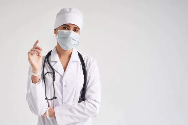 Ung läkare bär kirurgiska handskar och ansiktsmask, studio skjuten över vit bakgrund med kopieringsutrymme — Stockfoto