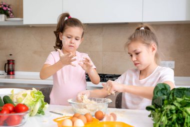 Mutlu aile komik çocukları hamuru hazırlıyor, mutfakta kurabiye pişiriyor. Kız kardeşler birlikte gülüyor.