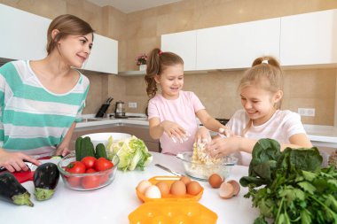 Anne ve iki kız mutfakta yemek pişiriyor ve eğleniyorlar, mutlu aile ve bekar anne kavramı. 