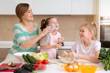 Anne ve iki kız mutfakta yemek pişiriyor ve eğleniyorlar, mutlu aile ve bekar anne kavramı. 