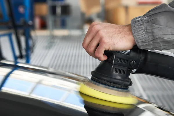 Manusia menggunakan polisher untuk memoles tubuh mobil hitam di bengkel — Stok Foto
