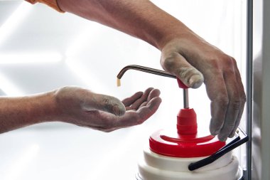 Tamirci, işten sonra kirli ellere sabun sürüyor.