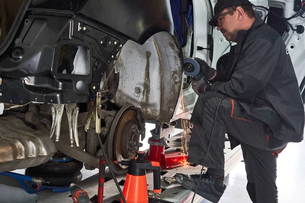 Reparação de serviço consertar carro danificado. Trabalhando com moedor de ângulo para fixar o corpo de metal . — Fotografia de Stock