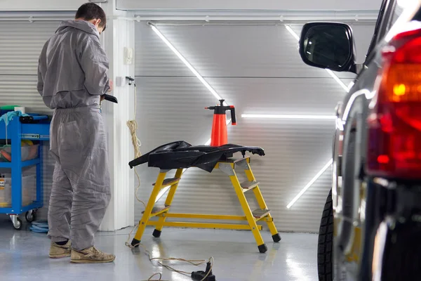 Car in auto repair shop with mechanic on a background — Stock Photo, Image