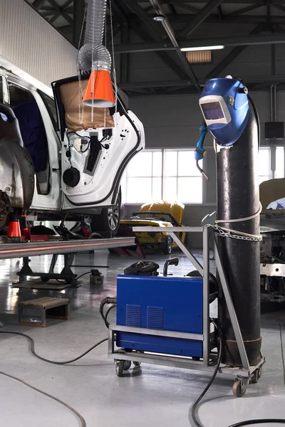 Équipement de soudage dans un poste de réparation automobile, casque suspendu à un réservoir d'essence, personne — Photo