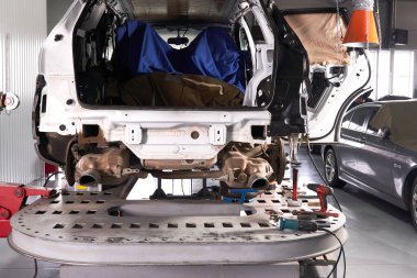 Araba tamirhanedeki asansör platformunda duruyor.