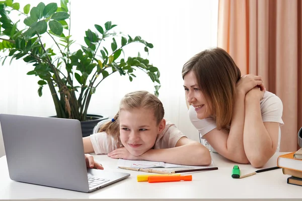 Anne, kızına ev ödevi için yardım ediyor. Karantinada evde eğitim kavramı. Mesafe öğrenirken eğlenceli — Stok fotoğraf