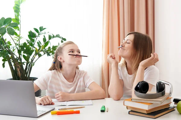 Evde uzaktan öğrenim görürken anne-kız eğleniyor, evde eğitim görüyor, kalemlerle bıyık yapıyor. — Stok fotoğraf