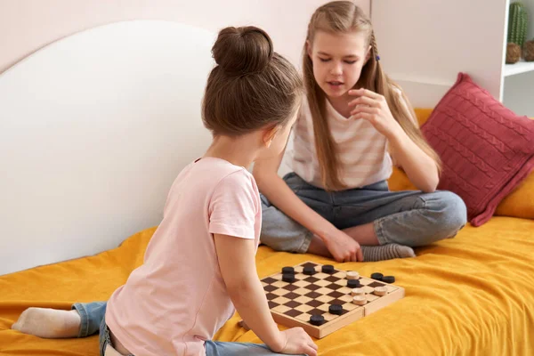Zwei Schwestern, die Checker spielen, auf einem schlechten Spaß zu Hause, glückliche Kinder Konzept — Stockfoto