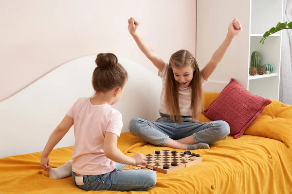 Zwei Schwestern, die Checker spielen, auf einem schlechten Spaß zu Hause, glückliche Kinder Konzept — Stockfoto