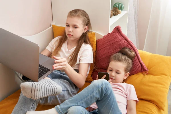Evde dizüstü bilgisayar kullanan iki kız kardeş. — Stok fotoğraf